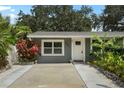 Inviting front exterior showcasing lush tropical landscaping, enhanced by a well-maintained lawn and concrete driveway at 4695 86Th N Ave, Pinellas Park, FL 33782
