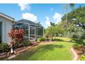 Backyard view with a screened-in lanai and lush tropical landscaping with vibrant plants at 5812 Garden Lakes Fern, Bradenton, FL 34203