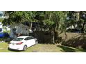 A house in need of repair, partially obscured by foliage, with a white car parked in front of a wooden fence at 710 25Th W Ave, Bradenton, FL 34205