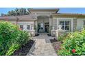 Inviting walkway leading to a charming home exterior, enhanced by lush landscaping with vibrant flowers at 766 Shadow Bay Way, Osprey, FL 34229