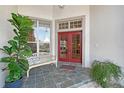 Welcoming front porch with red double doors, a bench, and potted plants, creating a cozy entry at 766 Shadow Bay Way, Osprey, FL 34229