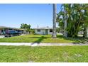 Charming home showcasing a well-maintained lawn and tropical palm trees, with a car parked on the side driveway at 1200 25Th W Ave, Palmetto, FL 34221