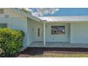 Close up view of home's entrance with storm door, tile porch and tidy landscaping at 1461 Porpoise Rd, Venice, FL 34293