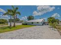 Charming single-story home with fresh landscaping and a gray brick driveway under a blue sky with clouds at 1461 Porpoise Rd, Venice, FL 34293