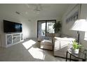 Bright living room featuring neutral tones, tile floors, and a sliding glass door to the balcony at 16904 Vardon Ter # 208, Lakewood Ranch, FL 34211