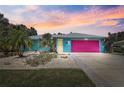 Charming home features a colorful exterior with a pink garage door and tropical landscaping at 2127 Corfell St, Port Charlotte, FL 33948