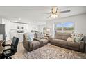 Inviting living room with a ceiling fan, two sofas and rug, adjacent to kitchen with white cabinets at 3108 Rock Sound St, Bradenton, FL 34208