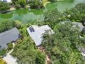 Aerial view of home with solar panels and lush greenery, nestled on a waterfront lot at 4443 Robin Hood W Trl, Sarasota, FL 34232
