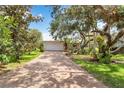 Charming home with a brick driveway, mature trees, and lush landscaping at 4443 Robin Hood W Trl, Sarasota, FL 34232