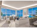 Open-concept living room with floor-to-ceiling windows offering views of the water and neutral furniture at 555 Quay Cmn # 1005, Sarasota, FL 34236