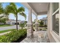 Charming covered front porch with stone columns and a cozy chair, perfect for relaxing outdoors at 5770 Long Shore Loop, Sarasota, FL 34238