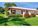 Beautifully landscaped front yard with red shutters and a white roof enhancing this home's curb appeal at 6701 12Th W Ave, Bradenton, FL 34209