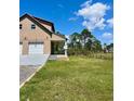 Side view of a charming two-story home featuring a two-car garage, a cozy porch, and a lush green lawn at 8412 Grove Blvd, Punta Gorda, FL 33982