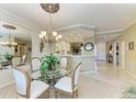 Bright dining area with elegant chandelier, glass-top table and views into the modern kitchen at 8422 Wethersfield Run # 103, Lakewood Ranch, FL 34202