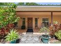 Inviting front entryway with stone pathway, colorful plants, and a charming welcome mat at 13719 Seminole Trl, Wimauma, FL 33598