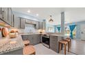 Modern kitchen featuring gray cabinetry, granite countertops, stainless steel appliances, and an open breakfast bar at 156 Myakka Rd, Venice, FL 34293