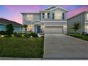 Two-story home featuring a manicured lawn, complemented by a two-car garage at twilight at 17330 Harvest Moon Way, Bradenton, FL 34211