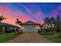 Beautiful home exterior with a brick-paved driveway, well-manicured lawn, and professional landscaping at dusk at 17725 Northwood Pl., Bradenton, FL 34202