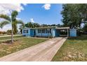 Light blue single-story home with a long driveway and mature landscaping on a sunny day at 22275 Belinda Ave, Port Charlotte, FL 33952