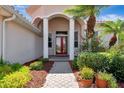 The red double door is framed by white columns and lush landscaping at 2729 Harvest Dr, Sarasota, FL 34240