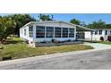 A cozy manufactured home with a large sunroom enclosed with awning style windows and a carport on a sunny day at 3308 Oakwood S Blvd, Sarasota, FL 34237