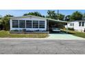 Charming manufactured home featuring a sunroom enclosed with windows and a carport with a car parked underneath at 3308 Oakwood S Blvd, Sarasota, FL 34237