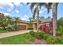 Beautiful home with manicured lawn, colorful flower beds, mature palm trees and a paver driveway at 4818 88Th E St, Bradenton, FL 34211