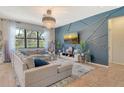 Stylish living room with a blue accent wall, large sectional sofa, and a modern chandelier, perfect for relaxation and entertainment at 5968 Snowy Egret Dr, Sarasota, FL 34238