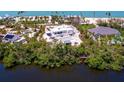 Aerial shot showcases a modern white home near the beach, featuring a pool, patio, and lush landscaping at 7647 Sanderling Rd, Sarasota, FL 34242