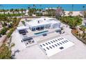 A modern white home with pool, lounge area and decorative hardscape detail in an aerial shot at 7647 Sanderling Rd, Sarasota, FL 34242