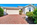 Paver driveway leading to a two-car garage, complemented by lush landscaping at 9022 Coachman Dr, Venice, FL 34293