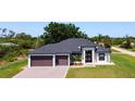 Beautifully landscaped home with a modern design, featuring a three-car garage and a well-manicured lawn at 10588 Kidron Ave, Englewood, FL 34224