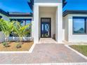 Inviting entryway with a striking modern front door, complemented by lush landscaping and a brick pathway at 10588 Kidron Ave, Englewood, FL 34224