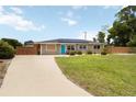 Lovely one-story home with a well-kept lawn, vibrant blue door, solar panels, and wooden fencing at 1212 Princeton Ave, Bradenton, FL 34207