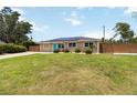 Inviting single-story home featuring a green lawn, blue door, solar panels, and a natural wood fence at 1212 Princeton Ave, Bradenton, FL 34207