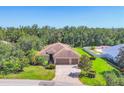 An aerial view of a landscaped single-story home featuring a three-car garage and brick paver driveway at 15208 21St E Ave, Bradenton, FL 34212