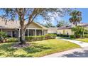 View of a charming home with a screened porch, mature tree, and meticulously maintained lawn at 1651 Red Oak Ln, Port Charlotte, FL 33948