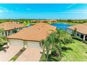 A well-manicured property with a red-tiled roof, paver driveway, and a tranquil lake in the background at 24065 Canterwood Way, Venice, FL 34293