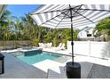 Resort-style backyard featuring a pool, hot tub, lounge seating, a dining set, and tropical landscaping at 2908 Gulf Dr, Holmes Beach, FL 34217