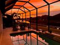 Relaxing screened-in pool with a stunning orange sunset view over the lake at 518 Chantilly Trl, Bradenton, FL 34212