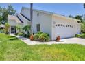 Charming home featuring a two-car garage, well-maintained lawn, and lush tropical landscaping at 6222 Country Club Way, Sarasota, FL 34243