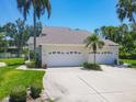 Charming home featuring a three-car garage, well-maintained lawn, and lush tropical landscaping at 6222 Country Club Way, Sarasota, FL 34243