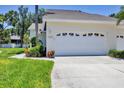 Garage exterior with white door, tropical plants in landscaping, and clear driveway at 6222 Country Club Way, Sarasota, FL 34243