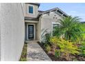 Home entryway featuring manicured landscaping with bushes and palm trees along the walkway at 8273 Shooting Star Rd, Sarasota, FL 34241