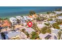 Close aerial view of a charming beach house surrounded by lush greenery and neighboring homes near the ocean at 880 N Shore Dr, Anna Maria, FL 34216