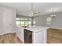 Kitchen island with stainless steel dishwasher and sink, featuring backyard view and modern pendant lighting at 12613 Oak Hill Way, Parrish, FL 34219