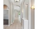 Elegant hallway featuring arched doorways, decorative lighting, neutral paint, and light tile flooring at 12642 Cara Cara Loop, Bradenton, FL 34212