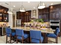 Gourmet kitchen featuring a large island, pendant lights, granite counters, and stainless appliances at 21225 Wacissa Dr, Venice, FL 34293