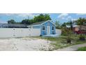 Light blue cottage with white trim, a green roof, a small front porch, and a white fence at 21403 Glendale Ave, Port Charlotte, FL 33952