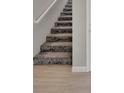 Carpeted staircase with wood-look flooring and white trim at 23233 Banbury Way # 302, Venice, FL 34293